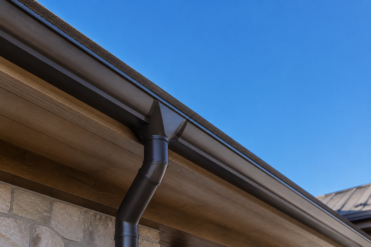 Seamless bronze aluminum gutter and downspout along a roof eave